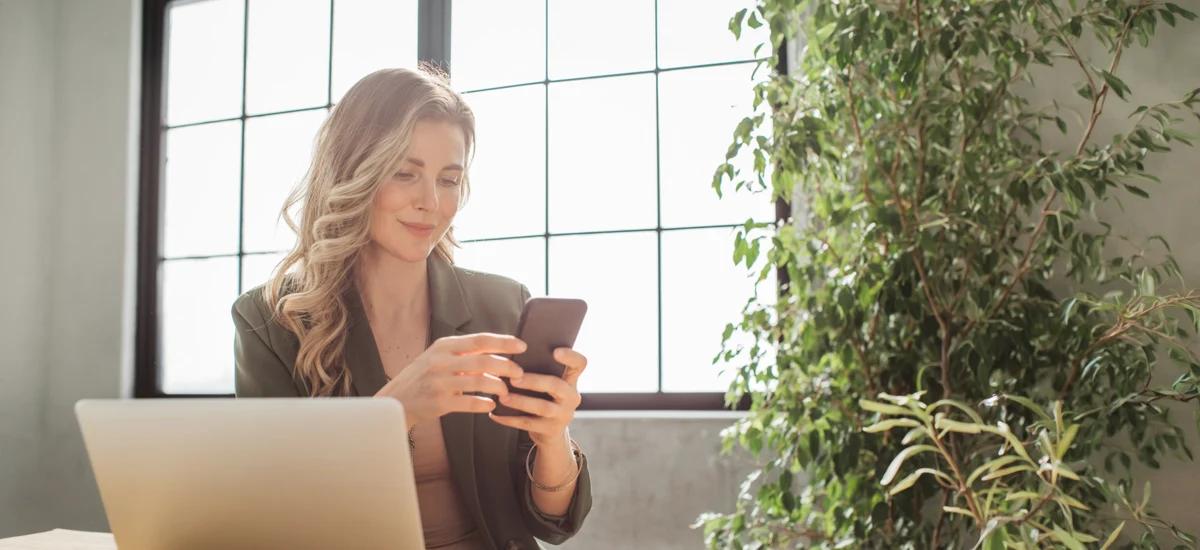 person am schreibtisch mit smartphone in heller umgebung