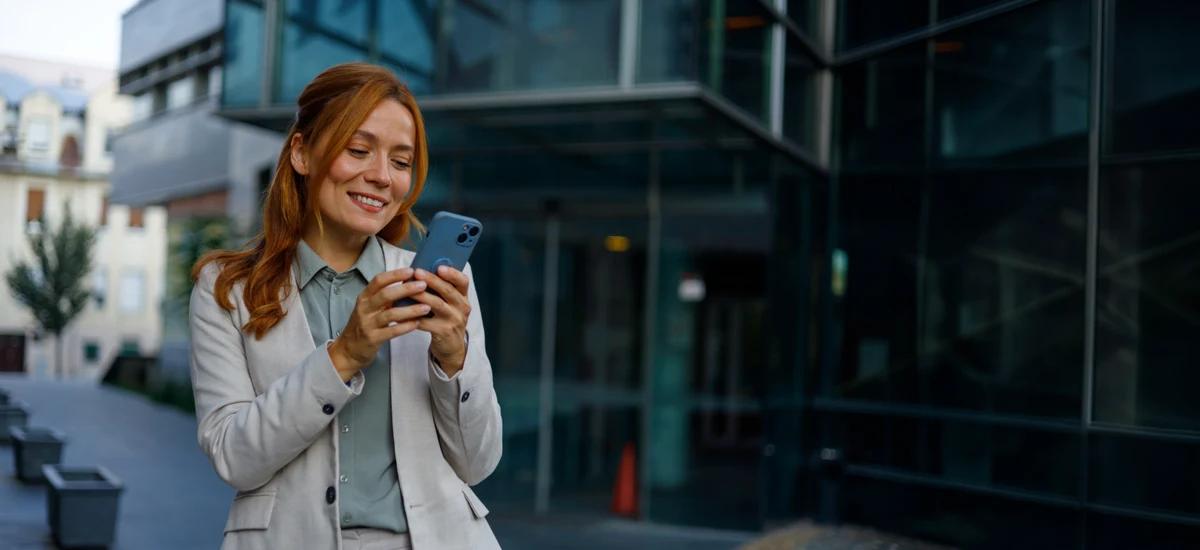 person steht vor gebaeude und schaut auf smartphone